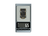 Flywoo Goku F405 SE flight controller weighing 6.5 grams on digital scale